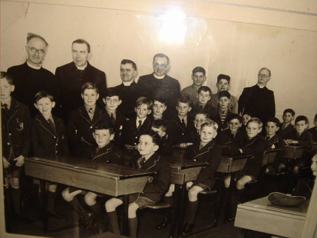 opening day.jpg - Desmond Deighan supplied this photo taken on the openning day of the school in 1953.Desmond was standing directly in front of the then Archbishop Gordon Gray, later to become cardinal. He can remember some of  the names of the other pupils, but you probably know them better than him, as he admits, his grey matter is now very rusty. he was surprised that we did not already have a copy. Have none survived the years? or his he the only hoarder! Back Row:- Bro Hastings, Archbishop Gordon Joseph Grey, Father McLennan, ?, Bertie D'Agostino. Lawrie Demarco, Bro O'Connell Boys standing:- John Shaw, Donald Shaw, Desmond Deighan, David Nelson, Michael Lewis, Freddy Triay,Mike Nagel, ?, ?, Seated :-  John Malone, John Neville, ?, Peter West, Tom Flaherty, Ronnie Rowley,?, ?, Gerry D'Agostino, ?(Thanks for corrections by John Shaw)